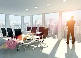 Mann steht in einem B&uuml;ro und guckt aus dem Fenster 